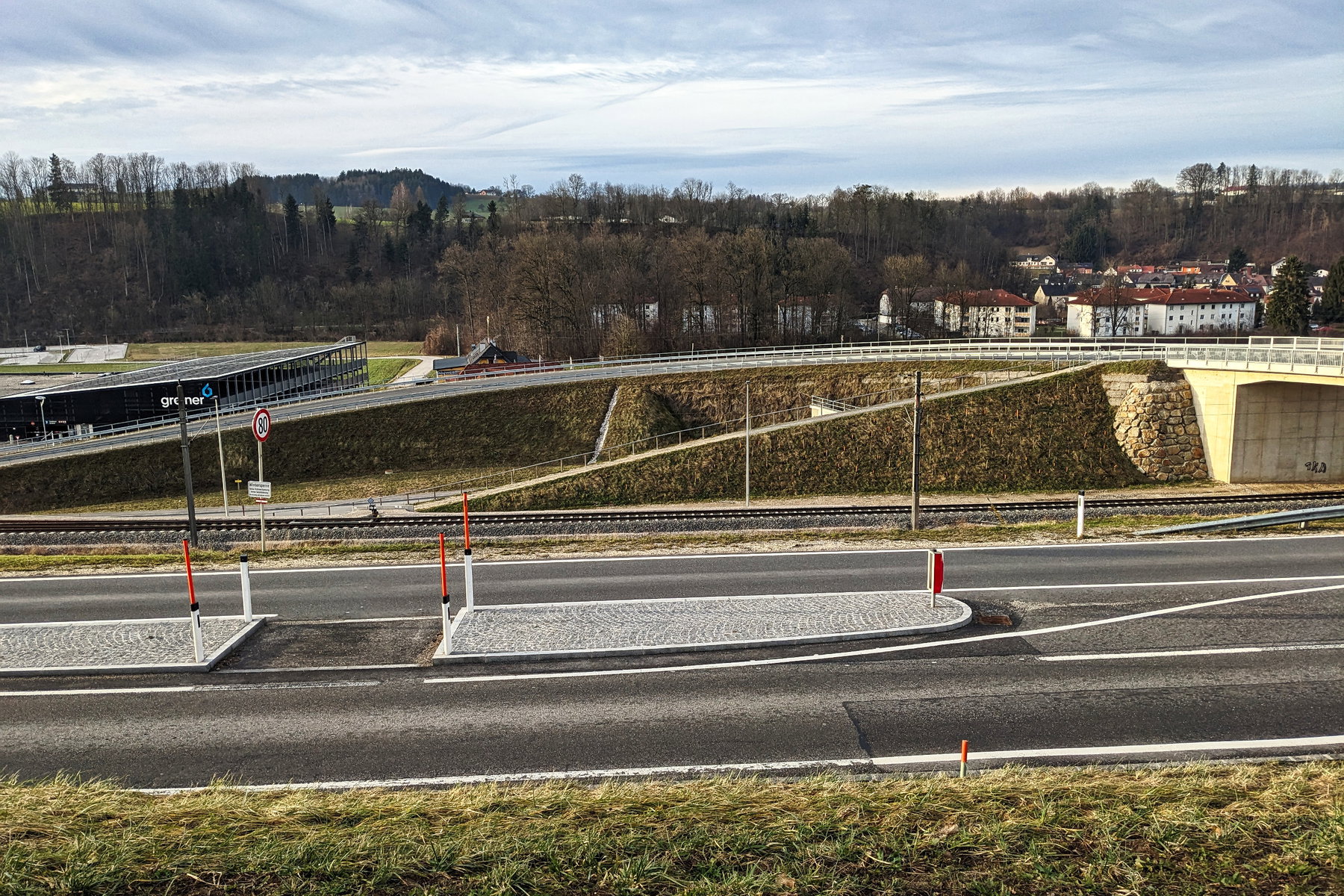 Eine der wenigen Kreuzungen ohne Wanderschilder. Erst wenn man die Straße überquert, die Brücke hinter der Leitplanke überschritten und den Gehweg bergab hinter den Gleisen überwunden hat, weist einen wieder eine gelbe Tafel auf die Richtung hin. Foto: Thomas Obermair