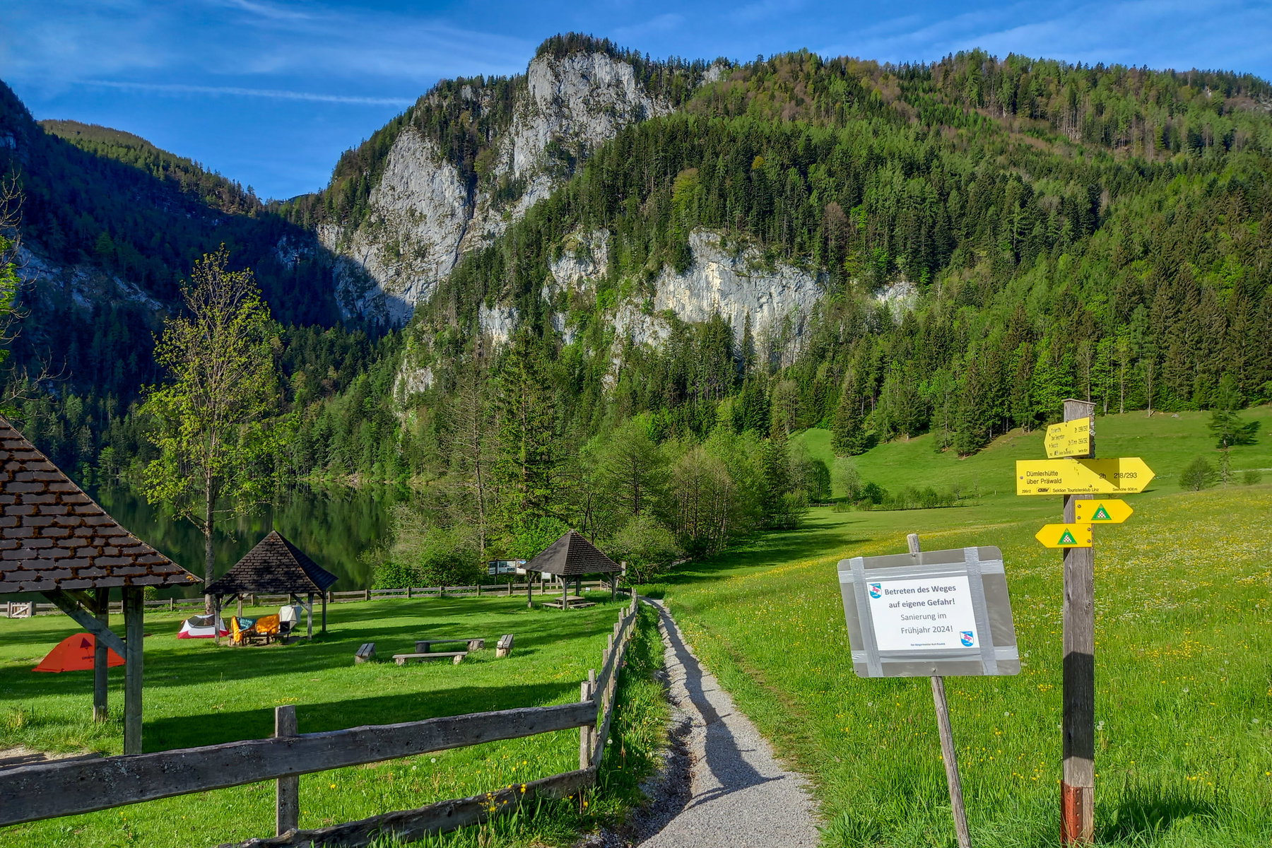 Der Weg führt zunächst am Ufer entlang und zweigt dann in den Wald ab. Ein Hinweisschild informiert, dass der Weg im Frühjahr 2024 saniert wird. Foto: Martina Friesenbichler