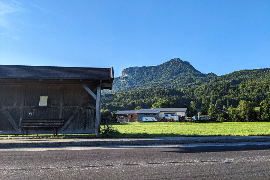 Die Haltestelle gegenüber mit unserem Gipfelziel im Rücken. Außerdem zu sehen: das Sägewerk am Beginn der Siedlung. Foto: Thomas Obermair