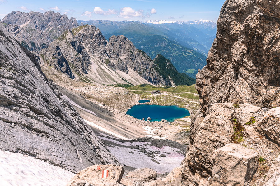Von oben schaut der See gleich noch beeindruckender aus. Vor den imposanten Dolomitengipfeln wirken die Karlsbader Hütte und der Laserzsee ganz unscheinbar. Im HIntergrund lugen schon die Hohen Tauern mit den schneebedeckten Gipfeln hervor. Das Foto ist übrigens nicht durch den Einsatz einer Drohne entstanden, sondern durch muskuläre Fleißarbeit hinauf zum Kerschbaumer Törl (nicht am GPX-Track!) Foto: Moritz Nachtschatt, POW AT